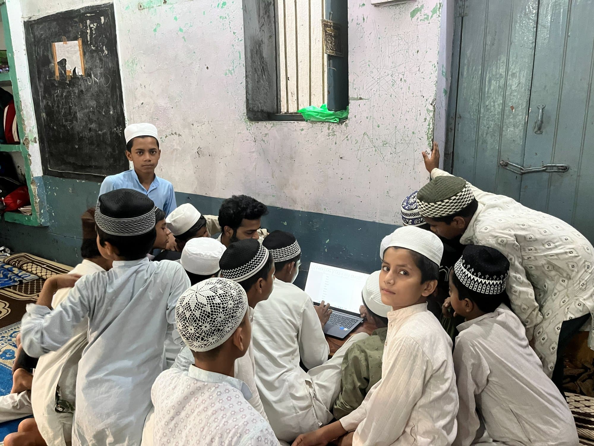 मदरसे की कक्षा में शाम के डिजिटल-साक्षरता सत्र के दौरान लैपटॉप के चारों ओर जुटे छात्र।